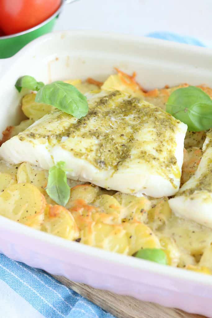 Ovenschotel met kabeljauw, courgette, tomaat en aardppelschijfjes. De vis wordt ingesmeerd met pesto.
